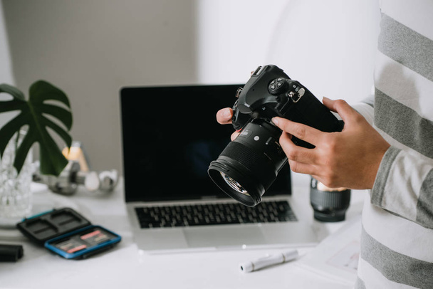 fotógrafo masculino segurando câmera digital acima da mesa em seu estúdio de fotos
 - Foto, Imagem