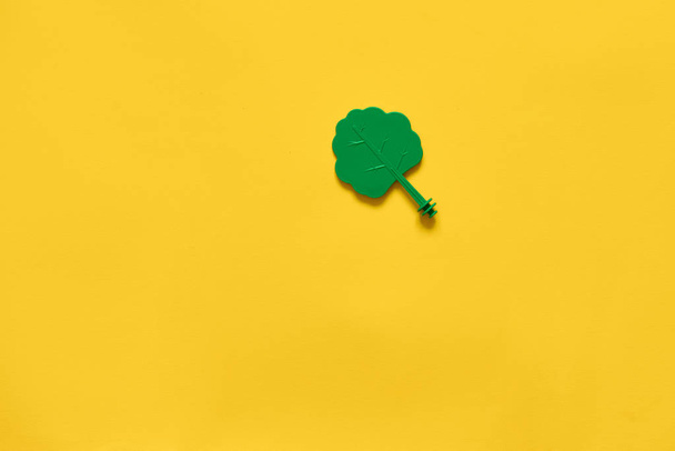 Plastic toy wood tree on yellow background. Minimal flat lay of ecology environment - Foto, immagini