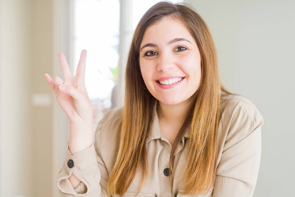 Beautiful young woman at home smiling with happy face winking at the camera doing victory sign. Number two. - Photo, Image