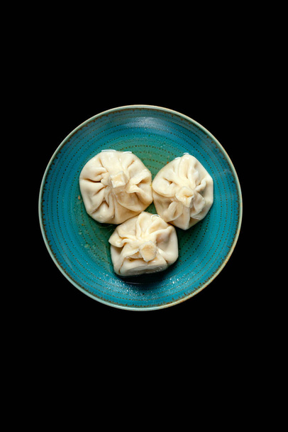 khinkali on a colored plate on a black background - Photo, Image
