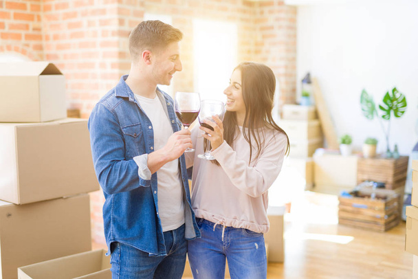 junges schönes Paar trinkt ein Glas Wein und feiert den Umzug in ein neues Haus - Foto, Bild