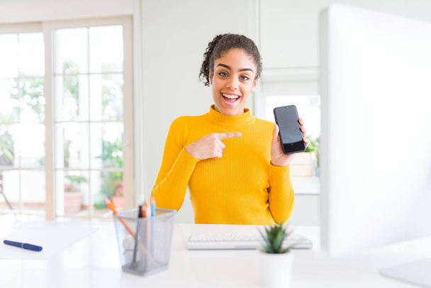 Young african american girl working using computer and smartphone very happy pointing with hand and finger - Foto, Bild