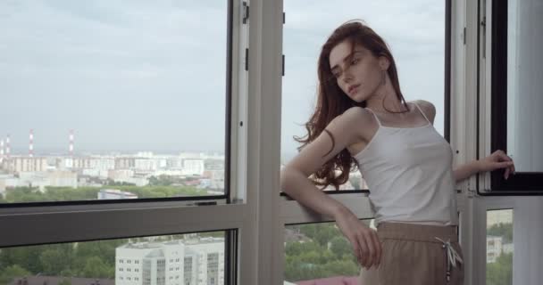 Jonge vrouw poseren in de buurt van open raam thuis. - Video