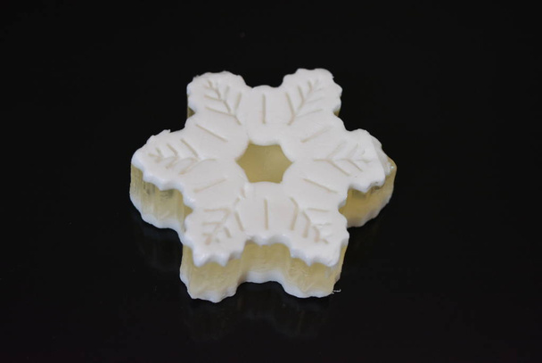 Beautiful white handmade fragrant soap in the form of one big snowflake lying on a black glossy surface. - Photo, Image