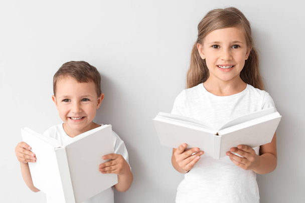Μικρά παιδιά με βιβλία σε ανοιχτόχρωμο φόντο - Φωτογραφία, εικόνα