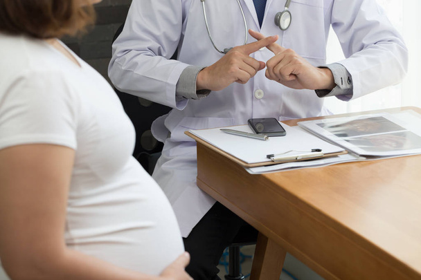 Doctor mostrando advertencia con señal de mano y hablando con la mujer embarazada. Prohibición durante el concepto de embarazo
 - Foto, Imagen