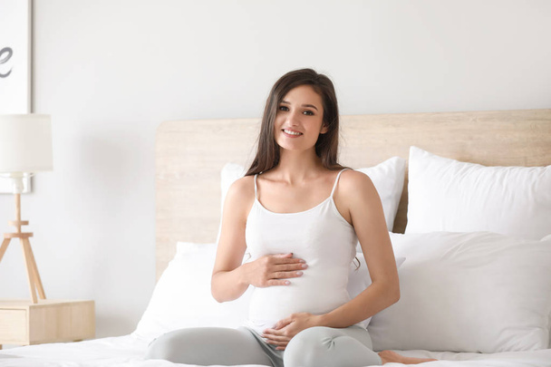 Красива молода вагітна жінка в спальні
 - Фото, зображення