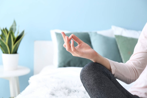 Young woman meditating on bed at home, closeup - Zdjęcie, obraz