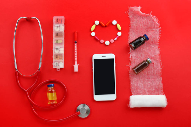 Teléfono móvil moderno con suministros médicos sobre fondo de color
 - Foto, Imagen