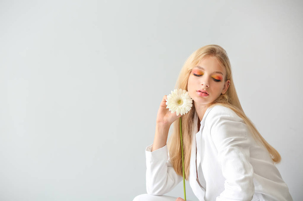 Beautiful young woman with gerbera flower on white background - Foto, imagen