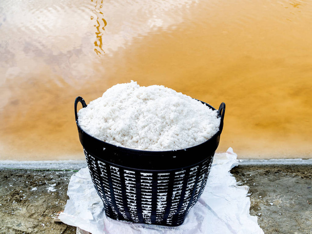 White sea salt in plastic basket near salt evaporation ponds. Sa - Photo, Image