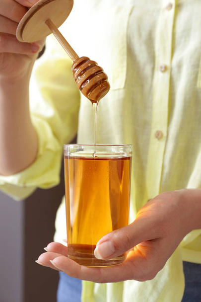 Mujer con vaso de dulce miel, primer plano
 - Foto, imagen