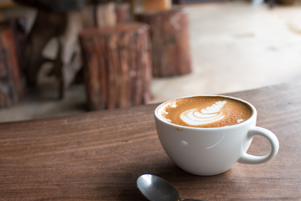 Κοντινό πλάνο του Κυπέλλου ζεστό καφέ τέχνης latte σε ξύλινο τραπέζι - Φωτογραφία, εικόνα