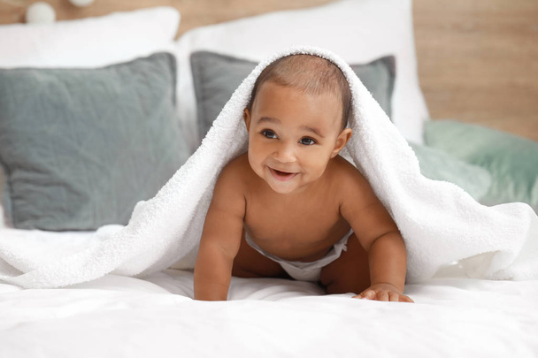 Cute African-American baby with soft towel on bed at home - Foto, Imagem