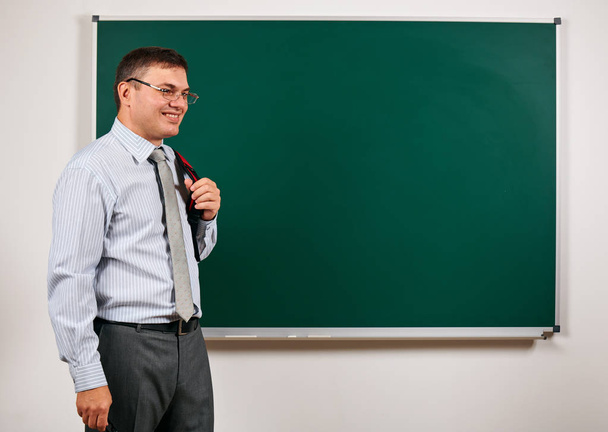 Porträt eines Mannes als Lehrer, der vor der Schultafel posiert - Lern- und Bildungskonzept - Foto, Bild
