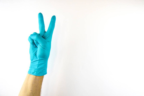 Mannelijke hand in medische handschoen op witte achtergrond. - Foto, afbeelding
