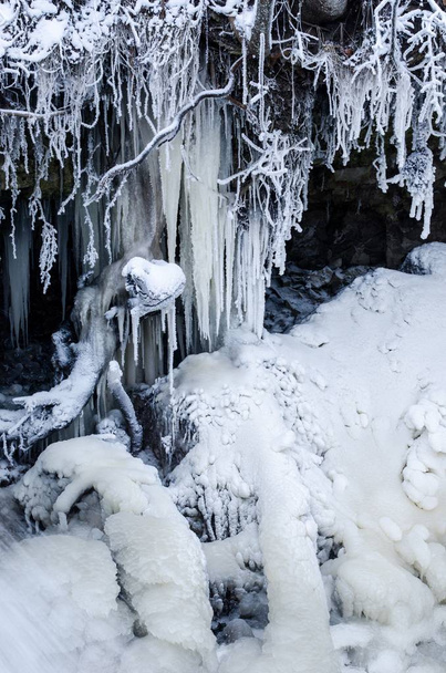 verschneiter Park an einem bewölkten Wintertag. gefrorener Wasserfall aus nächster Nähe. kuldiga, Lettland - Foto, Bild