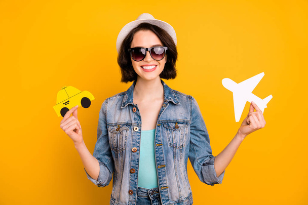 Photo of charming nice cute attractive funky funny positive girl wearing cap jeans denim comparing different kinds of transport while isolated with yellow background - Foto, Bild