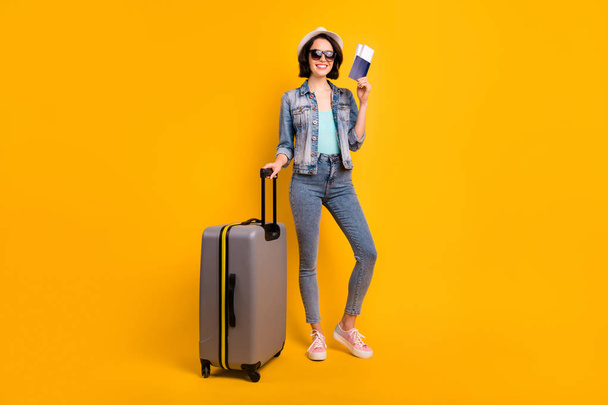 Full length body size photo of toothily smiling cheerful glad cute attractive nice girlfriend wearing jeans denim jacket rejoicing with being able to go abroad while isolated with yellow background - Zdjęcie, obraz