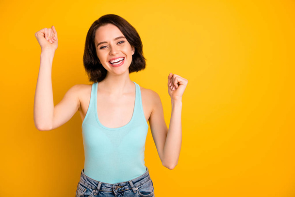 Photo of nice cheerful good glad girlfriend wearing jeans denim rejoicing with happiness of victory while isolated with yellow background - Zdjęcie, obraz