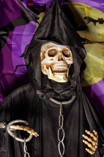 Halloween, Totenpuppe im schwarzen Kapuzenpulli mit Metallketten und Fußfesseln an den Händen. - Foto, Bild