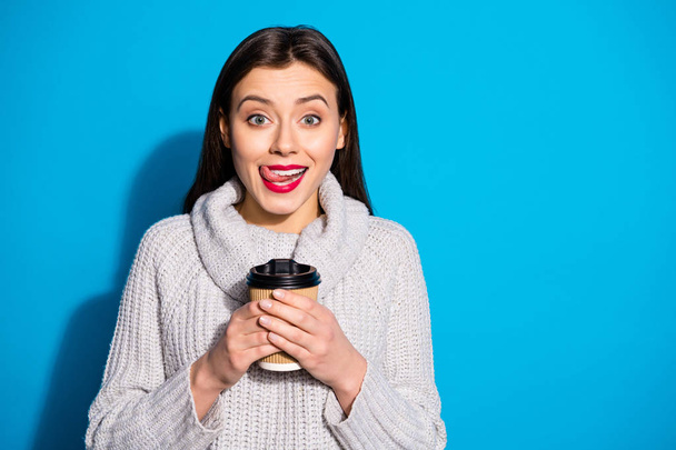 Portrait of funky person holding mug with hot beverage wearing gray sweater isolated over blue background - 写真・画像