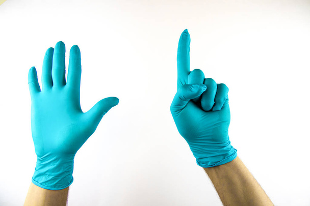 Mannelijke hand in medische handschoen op witte achtergrond. - Foto, afbeelding