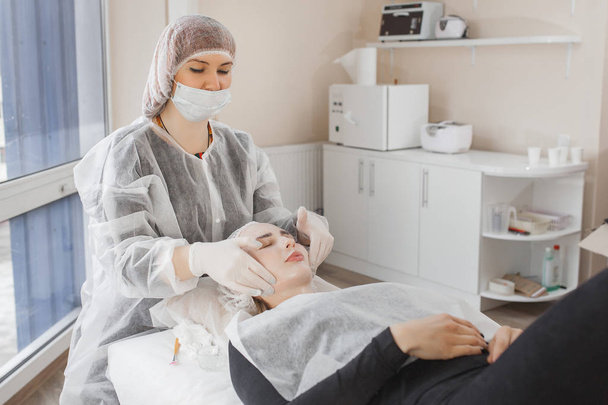 Master haciendo un procedimiento cosmético para su cliente. Tratamiento de la piel. mujer que realiza un procedimiento de atención facial. - Foto, imagen