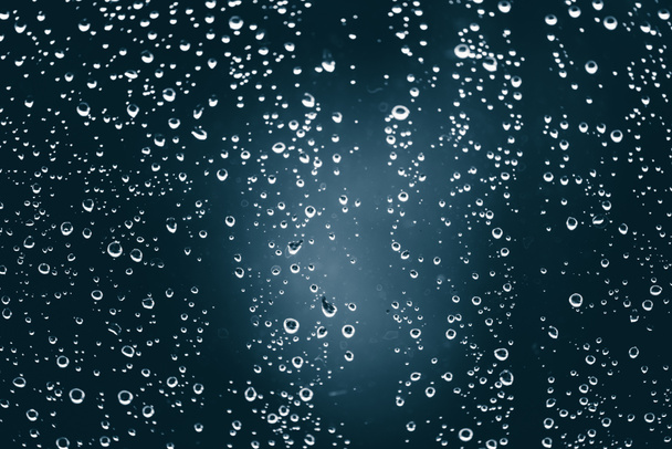 Vidrio de ventana sucio con gotas de lluvia. Fondo azul atmosférico con gotas de lluvia. Las gotitas y manchas se cierran. Textura transparente detallada en macro con espacio de copia. Clima lluvioso
. - Foto, Imagen