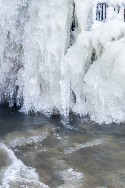 verschneiter Park an einem bewölkten Wintertag. gefrorener Wasserfall aus nächster Nähe. kuldiga, Lettland - Foto, Bild