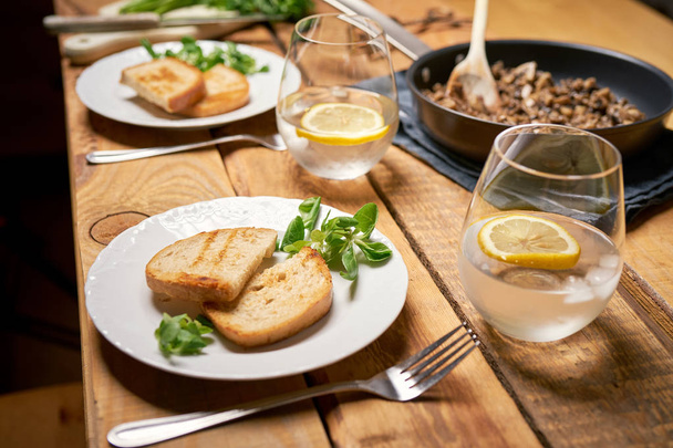 Gestoofde champignons in pan met toast en peterselie op houten tafel - Foto, afbeelding