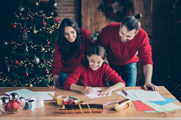 Photo of cheerful cute beautiful beaming comfort affectionate people wearing jeans denim red sweaters with parents watching their daughter wish present write letter for santa - Foto, afbeelding