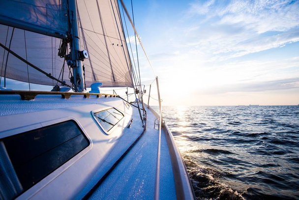 Plavím se při západu slunce. Pohled z paluby jachty na příď a plachty. Detailní záběr. Baltské moře, Lotyšsko - Fotografie, Obrázek