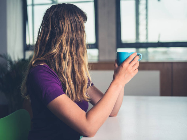 A young woman is drinking coffee in a city apartment - Photo, Image