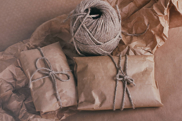 Process of packaging parcels. Pouch wrapped in brown craft paper and tie hemp cord. Crumpled paper texture background. Delivery service. Your order. Online shopping. - Фото, зображення