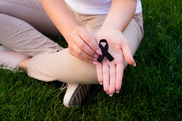 Het meisje houdt een zwart lint, symbool van kanker.  - Foto, afbeelding