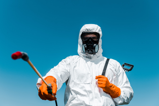 selective focus of exterminator in uniform and latex gloves holding spray outside  - Photo, Image