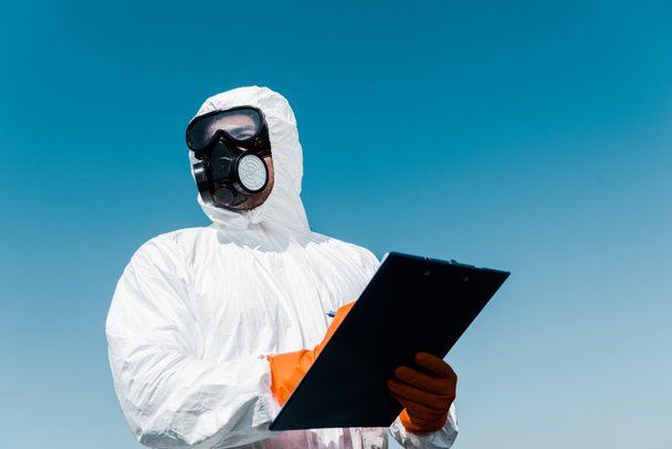 man in protective mask and uniform holding clipboard  - Foto, Imagen