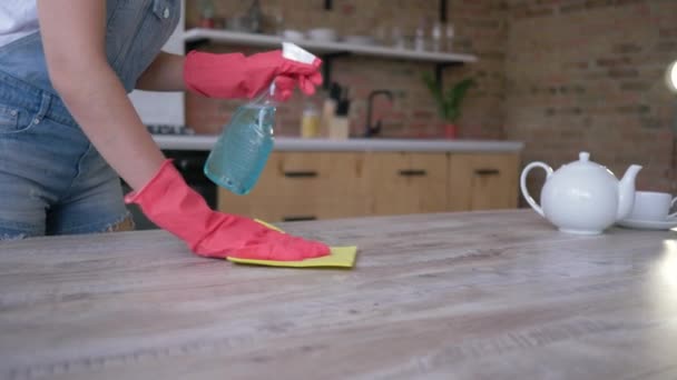 manos femeninas en guantes con trapo limpiando fácilmente la mesa del polvo y manchas con detergente en la cocina
 - Imágenes, Vídeo