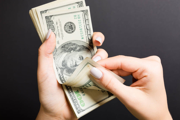 Вид сверху на женские руки, считающие деньги. Банкноты за сто долларов на красочном фоне. Концепция оплаты труда. Концепция взятки
 - Фото, изображение