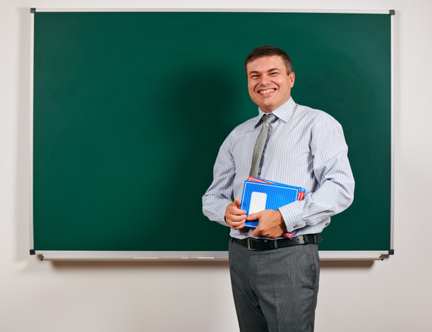 Portrait of a man as a teacher, posing at school board background - learning and education concept - Photo, Image