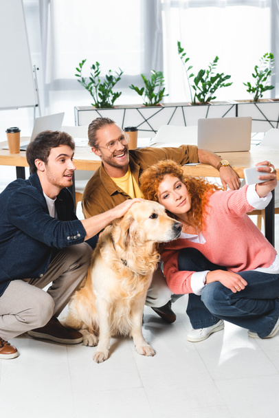 three smiling friends taking selfie with cute golden retriever - Photo, Image