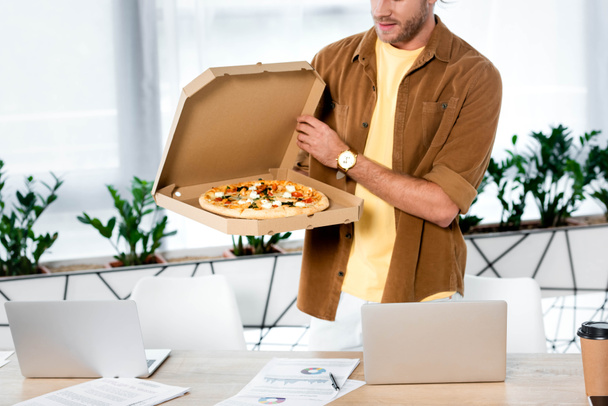 cropped view of businessman holding box with pizza in office  - Φωτογραφία, εικόνα