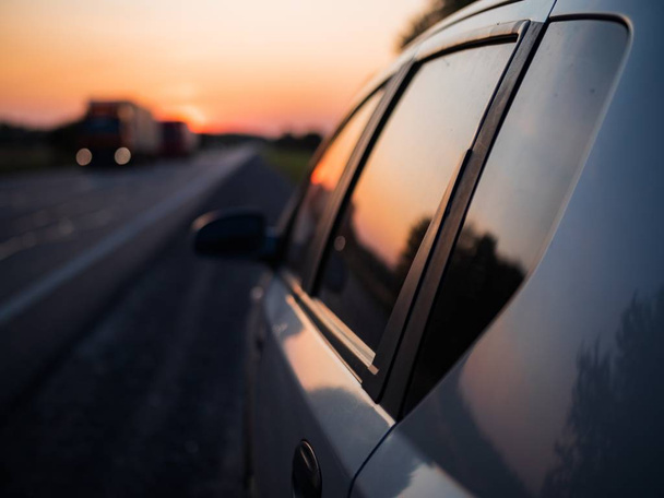 A selective focus closeup shot of a gray car window and door during sunset - Foto, Bild