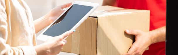 panoramic shot of delivery man holding package near woman with digital tablet  - Photo, image