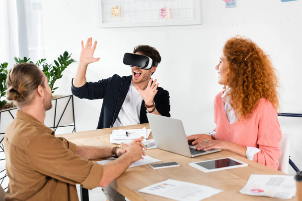 smiling businessman with virtual reality showing hands and friends looking at him  - Foto, Bild