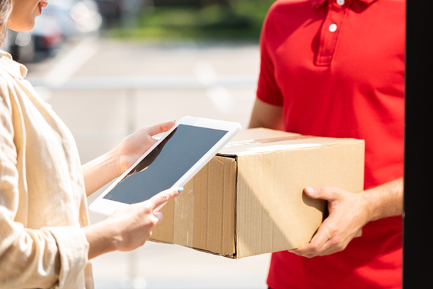 vista ritagliata di consegna uomo holding box vicino alla donna con tablet digitale
  - Foto, immagini