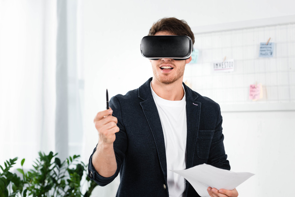 businessman in shirt with virtual reality headset holding pen and papers - Фото, зображення