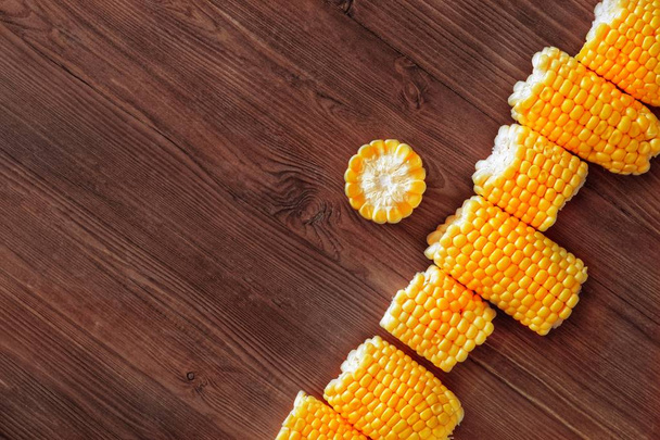 Flat lay composition of fresh corn cobs on a wooden background. Top view, copy space for text - Fotografie, Obrázek