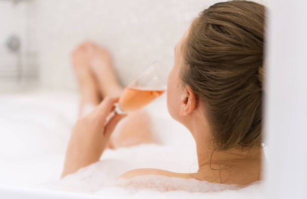 Жінка з келихом вина розслабляється у ванній. Вид ззаду
. - Фото, зображення